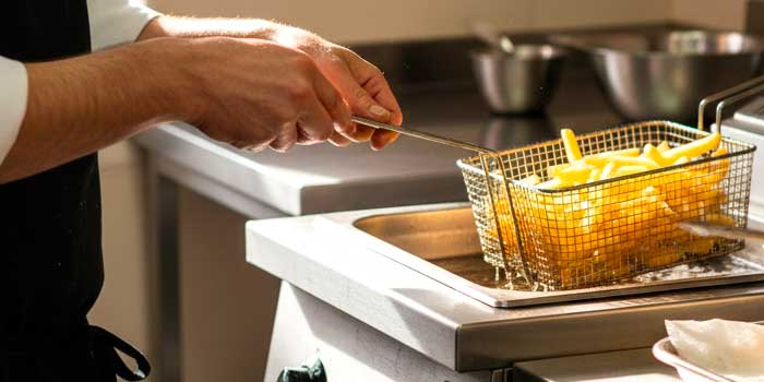 Unas manos de cocinero con una freidora profesional