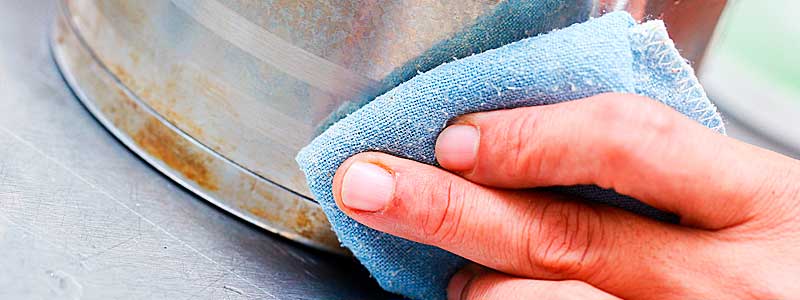 Mano enguantada limpiando un mueble de acero inox